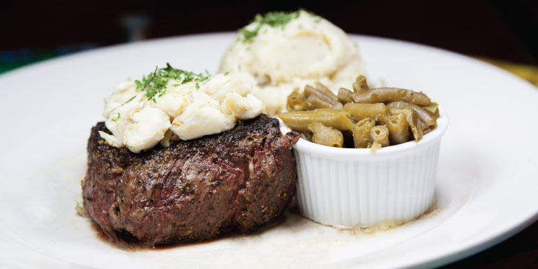 Grilled steak topped with crabmeat, served with mashed potatoes and green beans